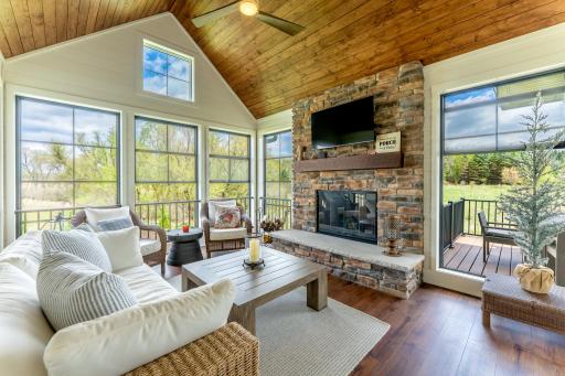 Step from the kitchen or dining area out to the screen porch with wood accents and stone woodburning fireplace.