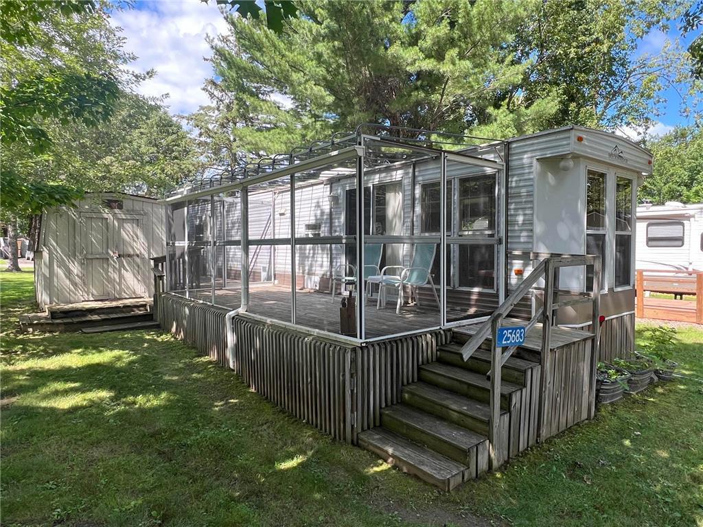 A closer look at the park model's exterior, featuring the large deck with screen porch.