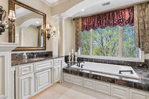 Primary bathroom with dual granite vanities, soaking/jetted tub, and separate tiled shower