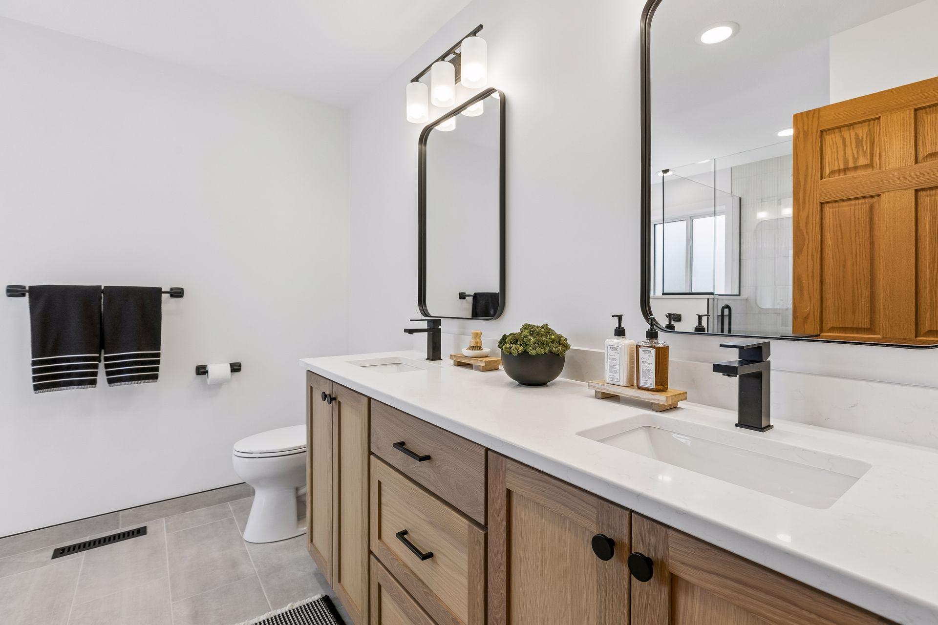Completely remodeled primary bath with a custom white oak double vanity, quartz countertops, tiled floors, modern fixtures, and stylish finishes.