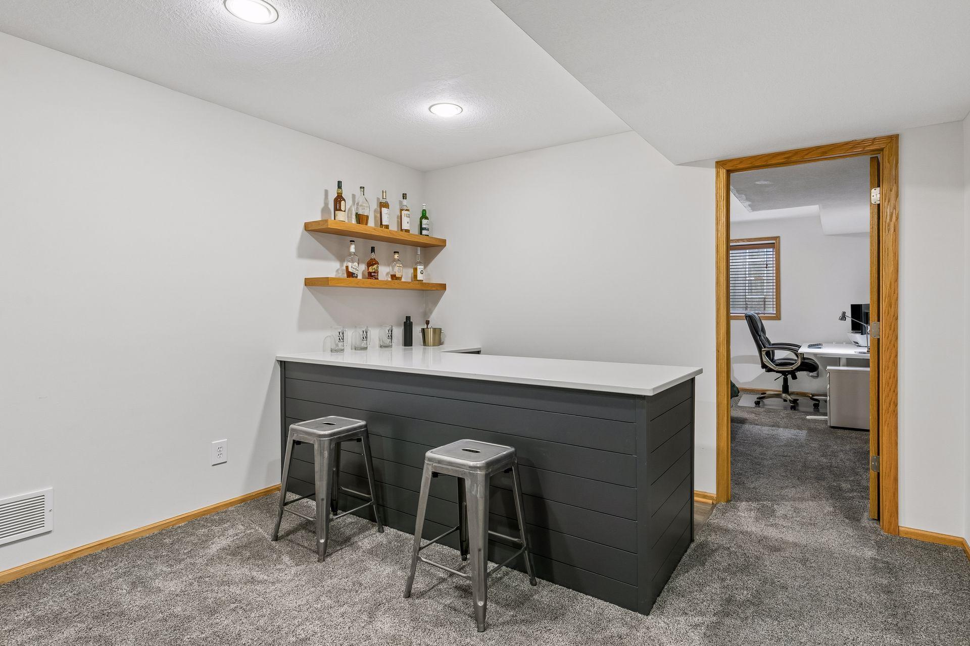 The perfect complement to the lower-level family room is this stylish built-in bar with seating and open shelving.