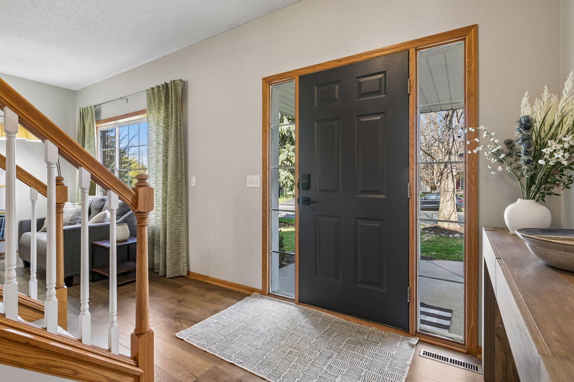 The bright, welcoming entry, with warm wood flooring and sidelight windows, creates an open, inviting feel.