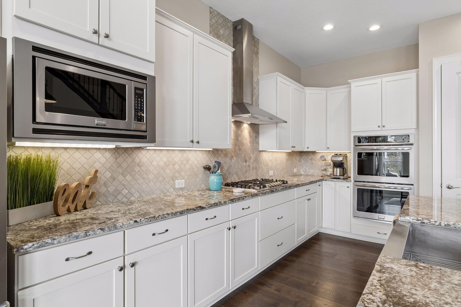 Beautiful backspash, under cabinet lighting, a 5 gas burner stove with a stainless steel hood.