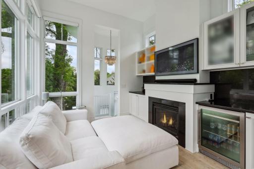 Primary bedroom sitting room with gas fireplace and beverage fridge for ultimate relaxation. Spiral staircase leads down to the lower level.