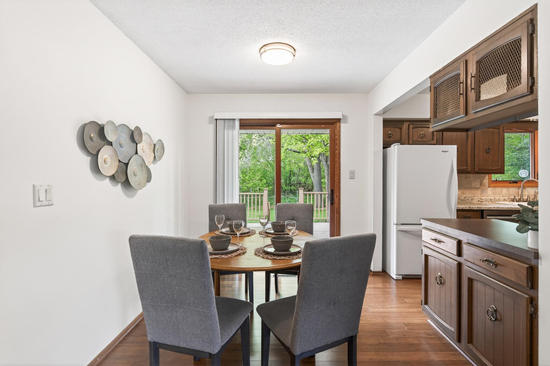 Dining area looks out on nature-filled backyard with mature trees