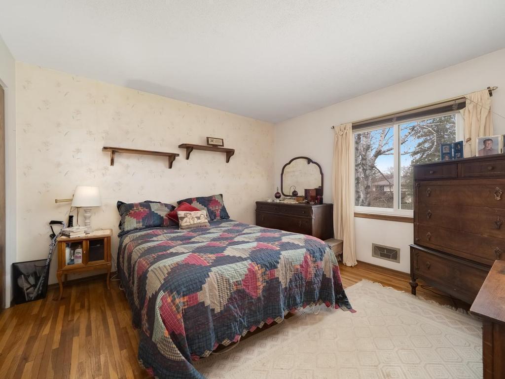 1 of 2 main floor bedrooms with hardwood floors and newer window