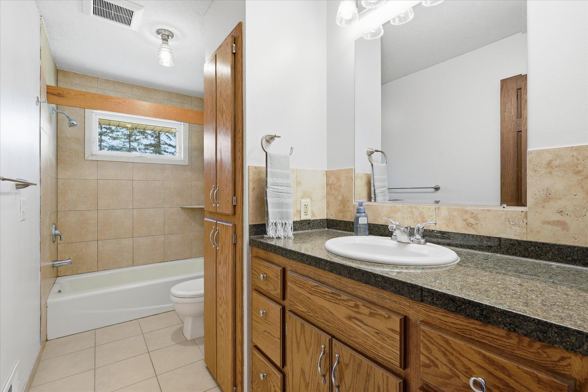 The tiled full bath on the upper main level. Lots of cabinet space for all your bath and linen needs.
