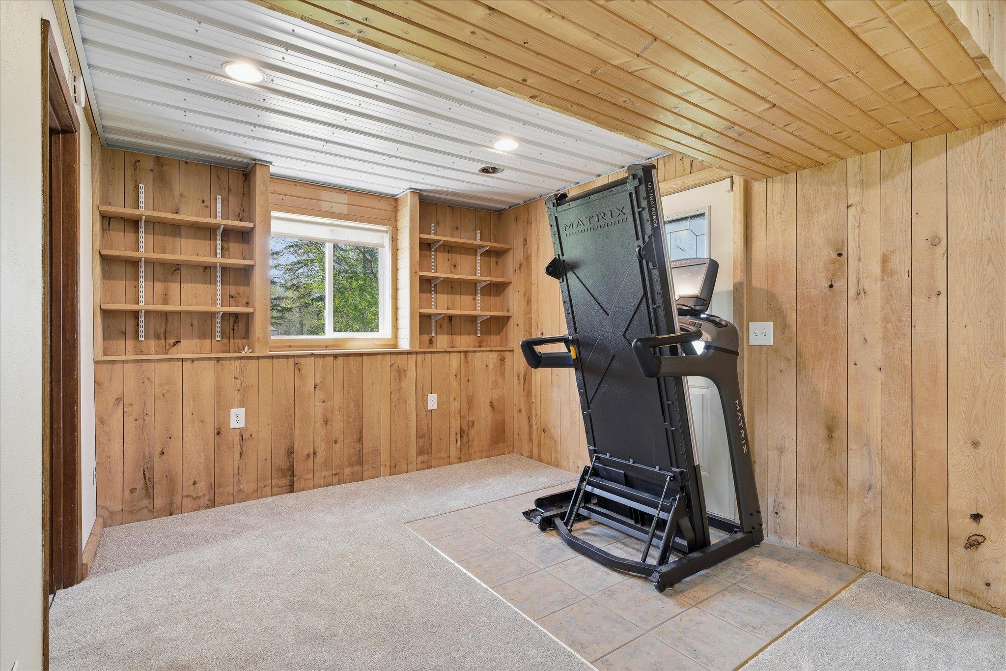 The additional space in the lower level includes the built in shelves for showing off your favorite items. The area by the walkout door is tiled. The treadmill will be removed.