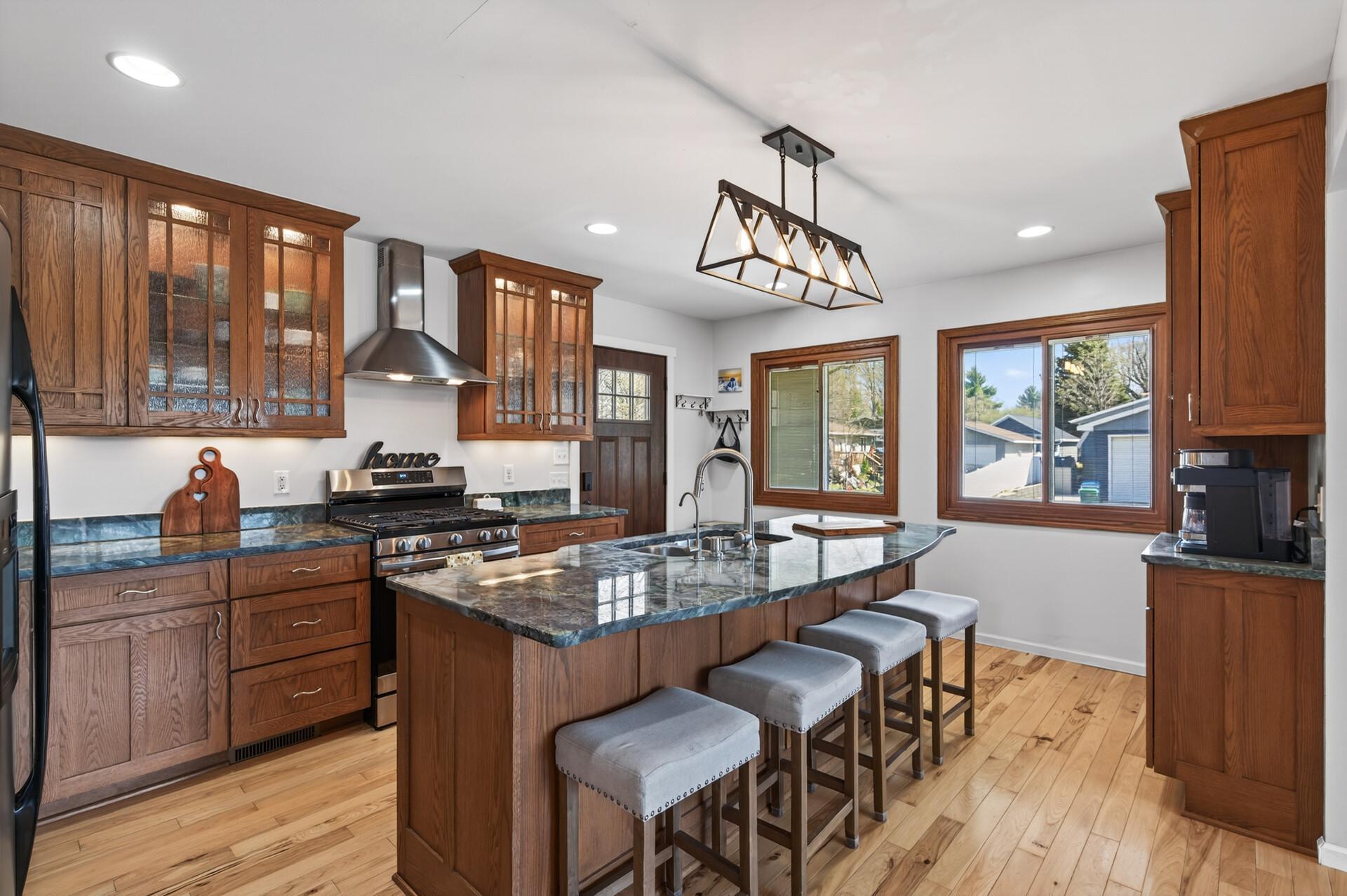 Complete with rich wood cabinetry, updated appliances, modern lighting, and an oversized island with seating.
