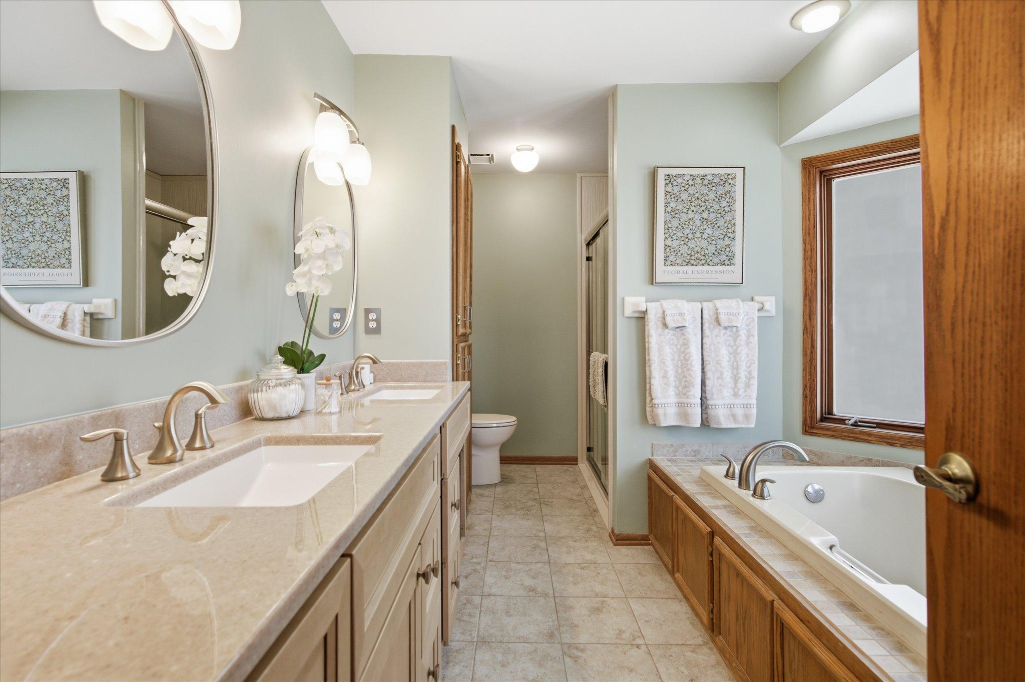 Gorgeous newly remodeled full bathroom in the primary suite with new vanity, tiled flooring, shower surround, mirrors and fixtures. This bathroom also offers its own built in linen closet.
