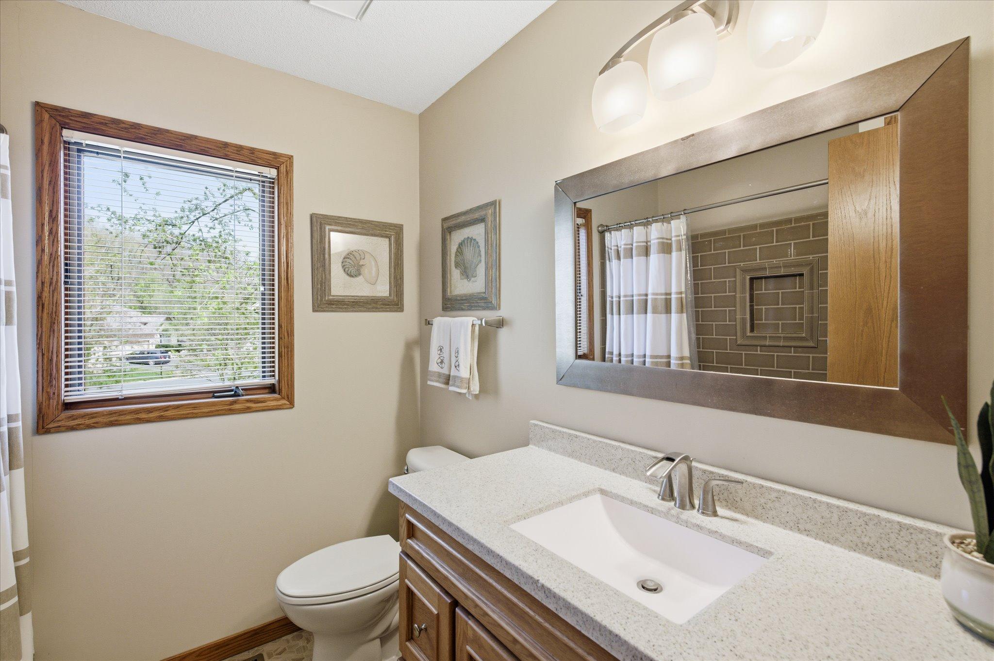 Updated full bathroom on the upper level with newer vanity, tiled shower surround, mirror and fixtures.