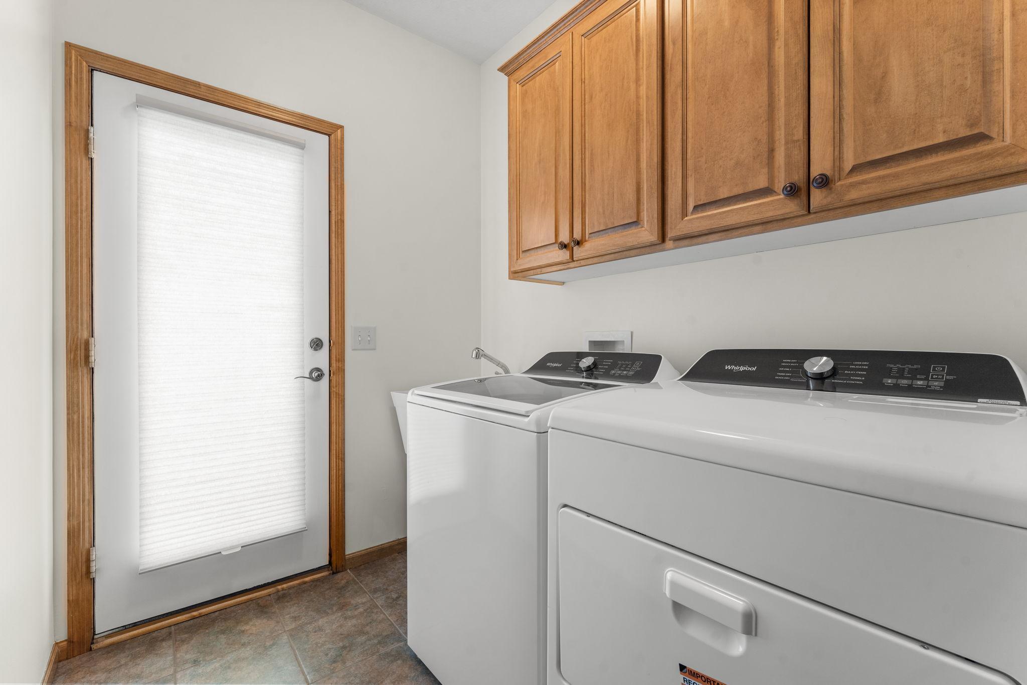 Completing the main level is a highly desirable laundry room with a utility sink, cabinetry, exterior access, and proximity to the attached two-car garage.