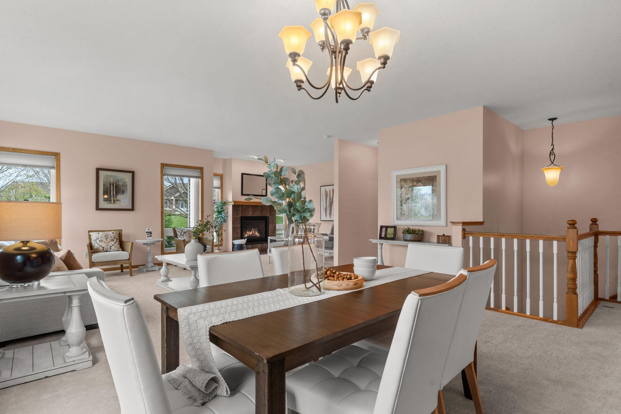 Adjacent to the kitchen is a formal dining room with plush carpeting, a chandelier, and a large window that fills the space with natural light—perfect for hosting gatherings.