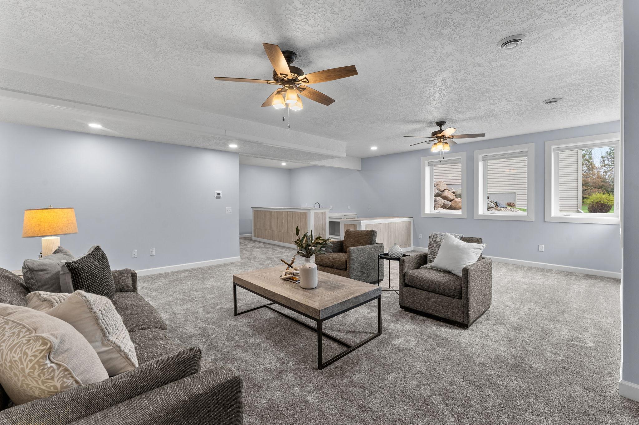 The expansive family room features two ceiling fans for added comfort, cozy carpeting, and abundant natural light.