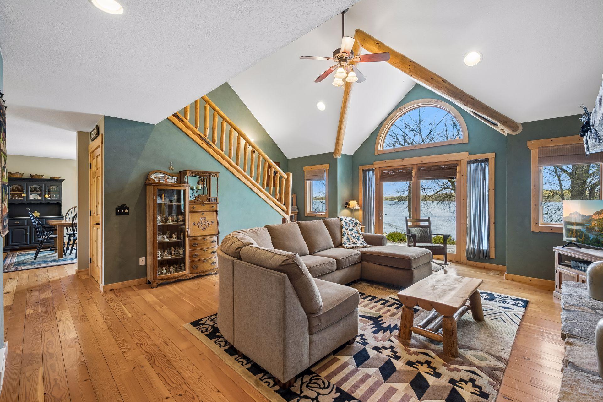 Inviting vaulted lakeside living room with panoramic water views. Northwoods charm creates the perfect setting to take the outside in and just breathe.