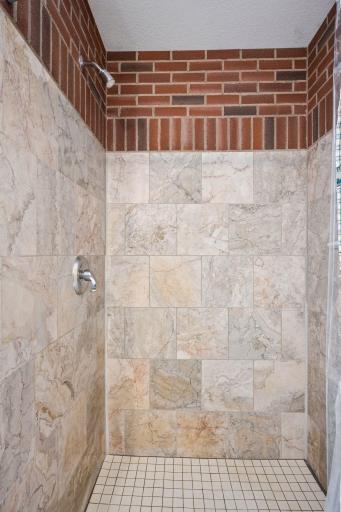 Walk in tile surround shower with accent brick decor.