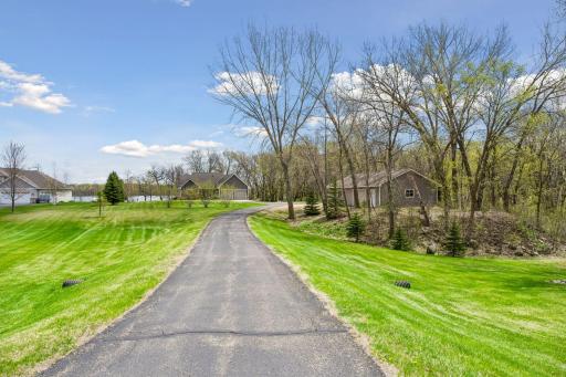 Paved driveway with 2nd garage on the right, mound system and well on the left. The home is nestled back near the waterfront for ultimate privacy. This property is located at the end of the paved street and next to woods.