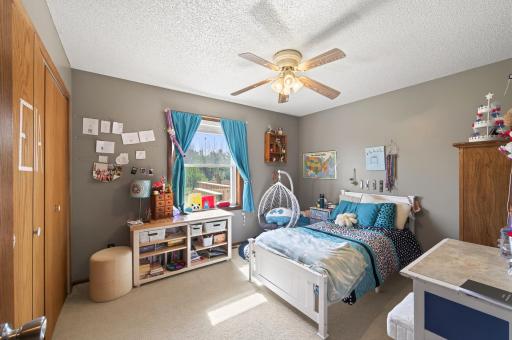 Second upper level bedroom also has neutral tones, abundant natural light, and a ceiling fan.