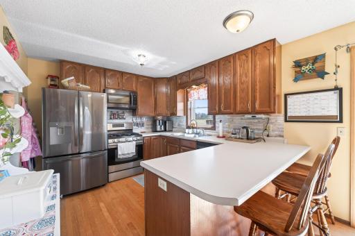 The kitchen features rich wood cabinetry, a stylish backsplash, and stainless steel appliances.