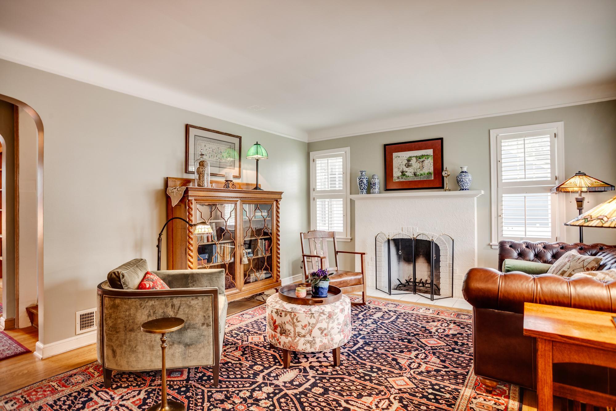 A welcoming foyer enters to the beautifully appointed living room offering a sophisticated and comfortable atmosphere, anchored by a lovely, wood-burning fireplace and enhanced by abundant natural light from multiple windows with plantation shutters.