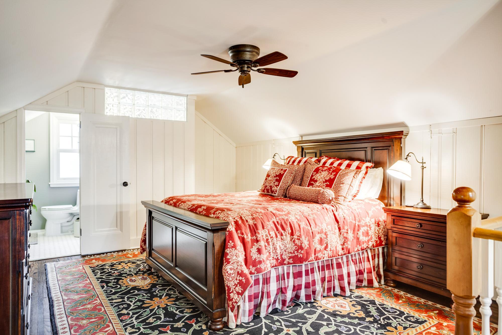 Upstairs, the home truly shines with an incredible primary suite retreat. Carpeted stairs lead to a spacious and airy sleeping area tucked beneath charming, sloped ceilings, creating a cozy yet open feel.