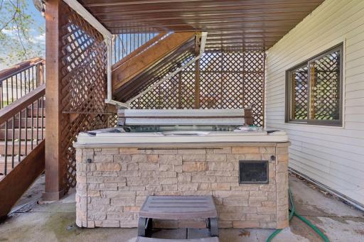 The hot tub is tucked at the end of the porch next to the stairs that lead to the deck.