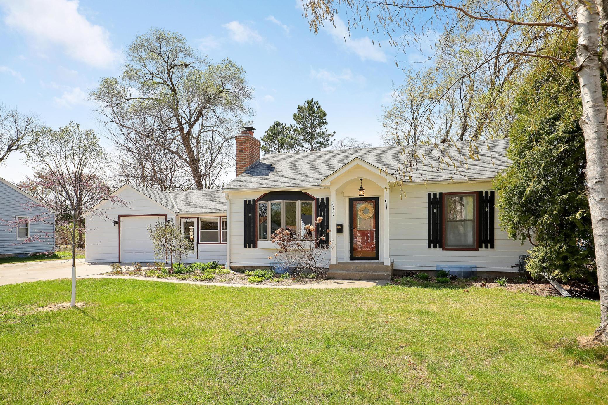 Assorted perennials to bloom soon will enhance the curb appeal of this gorgeous home.