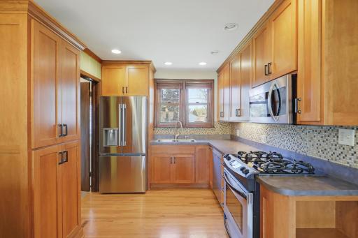 Gorgeous wood cabinetry and a playful tile/glass backsplash fuse well together. The window looks over the backyard.
