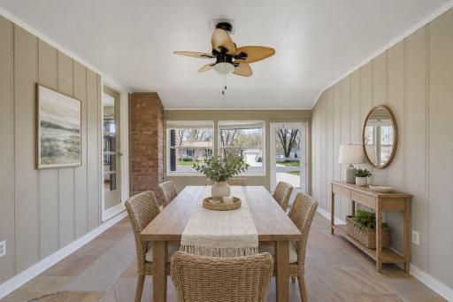 The verdant sunroom/breezeway can accommodate seasonal gatherings depending on your lifestyle. This is virtually-staged as a dining space.