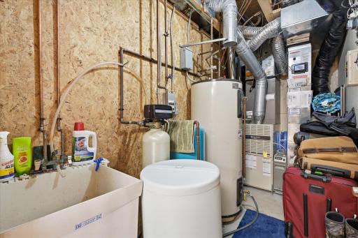 The utility room features a utility sink, an 82-gallon water heater, a water softener, a 2-y.o well pressure tank and a UV light bacteria killer on the furnace.