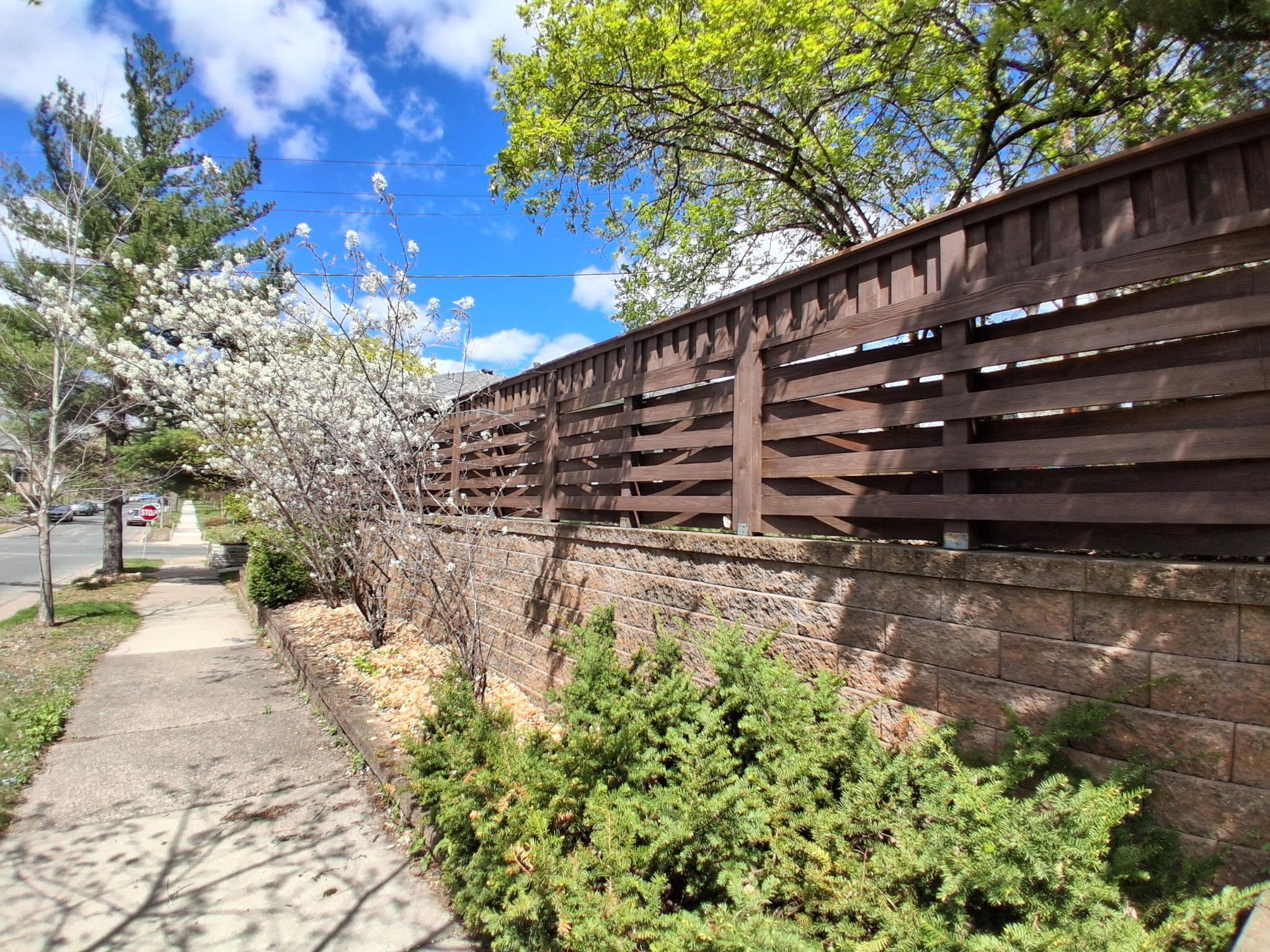 Newly finished fence and retaining wall along side of yard affords privacy and low maintenance