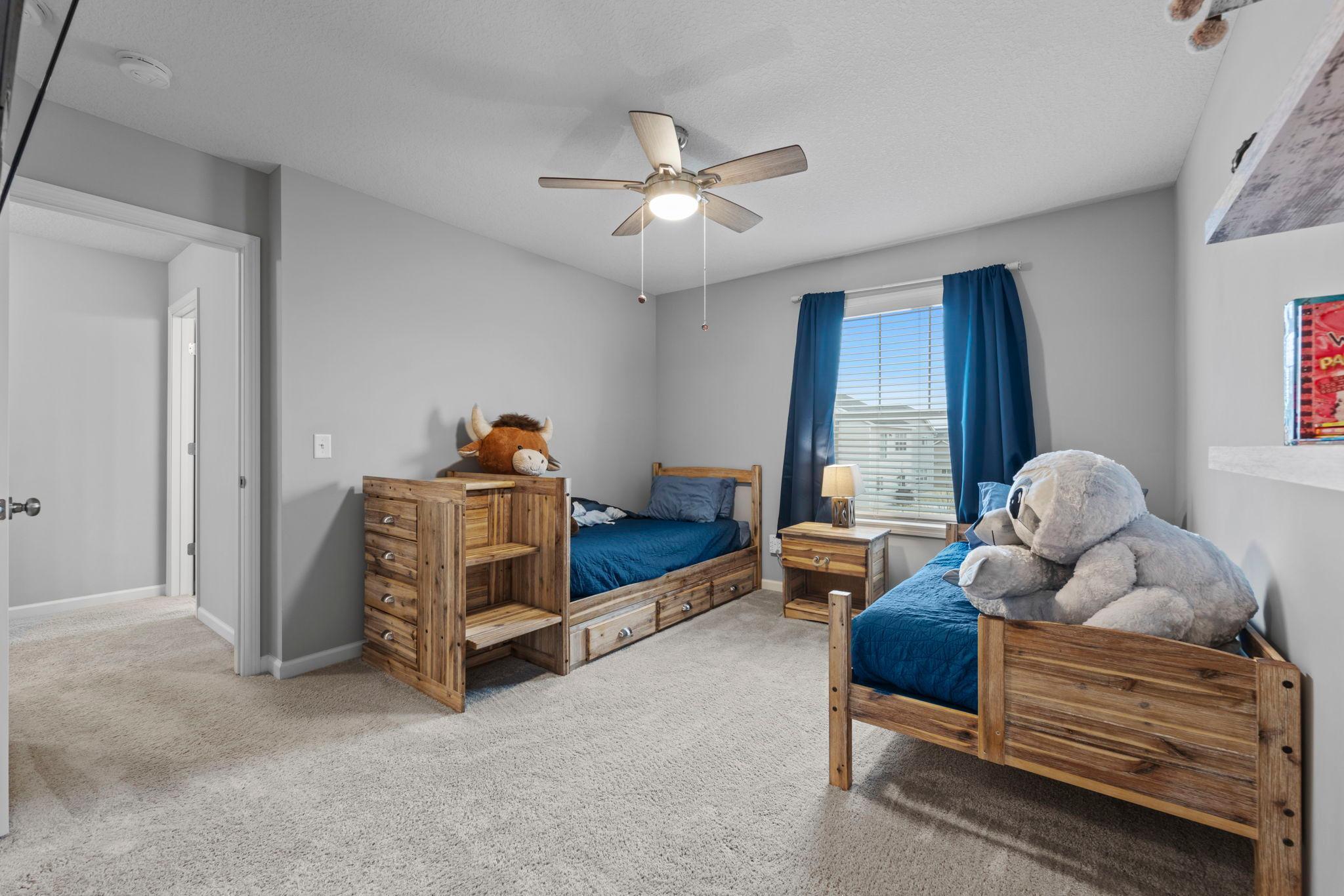 2nd Bedroom on upper level with custom window treatments, ceiling fan, tinted windows, built-in shelving.