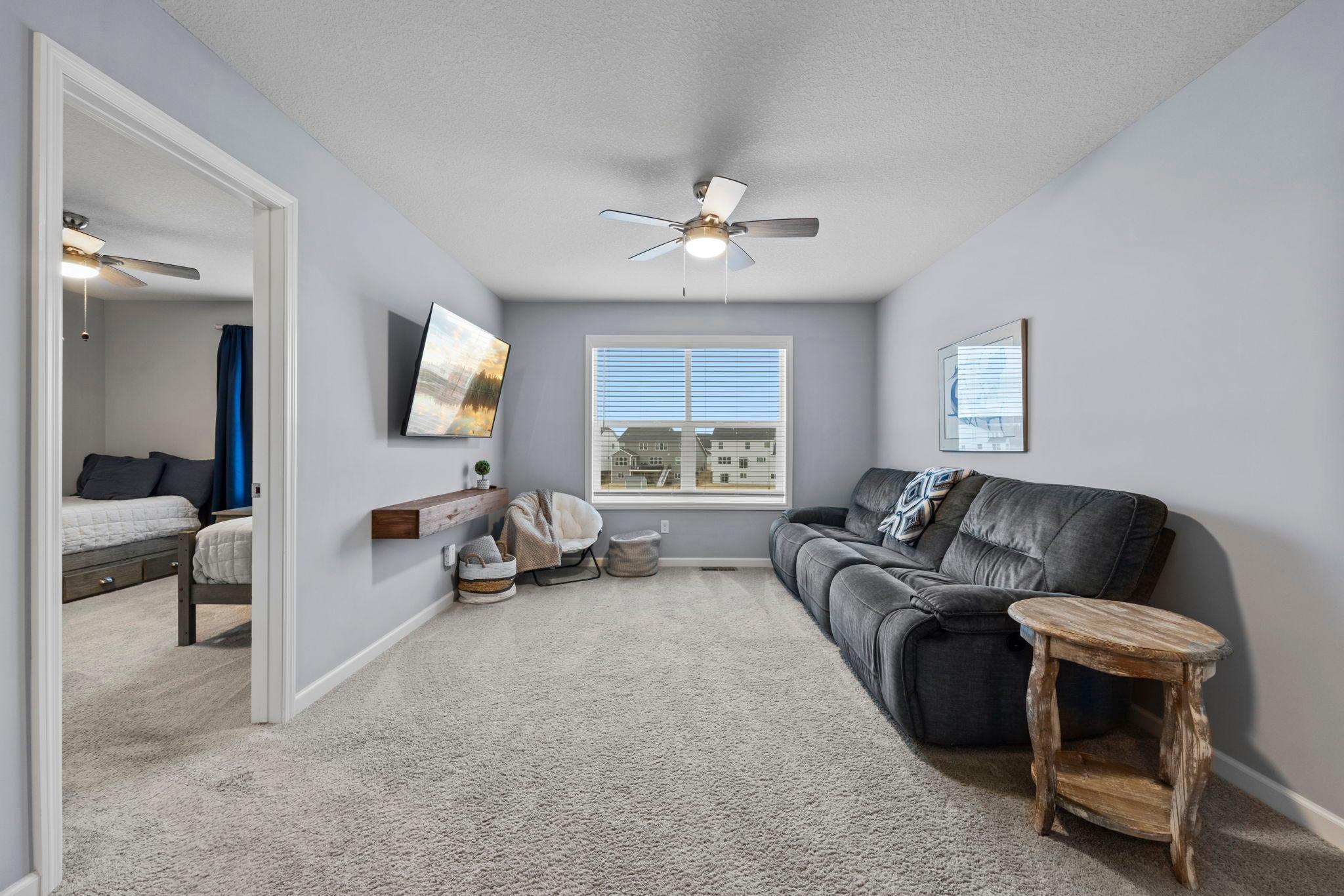 Upper-level loft with tinted window, built-in custom shelf, ceiling fan, knockdown ceilings throughout