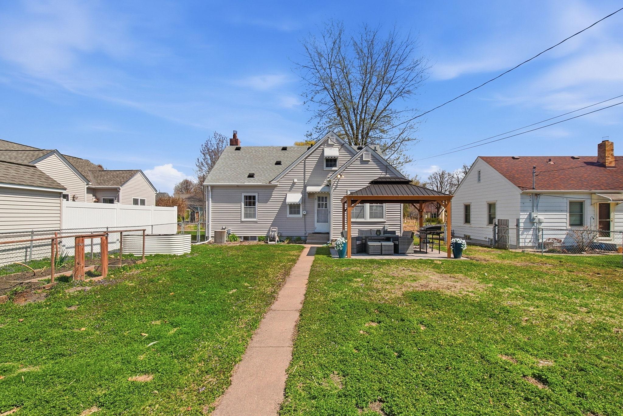 Backyard with paver patio and raised garden beds.