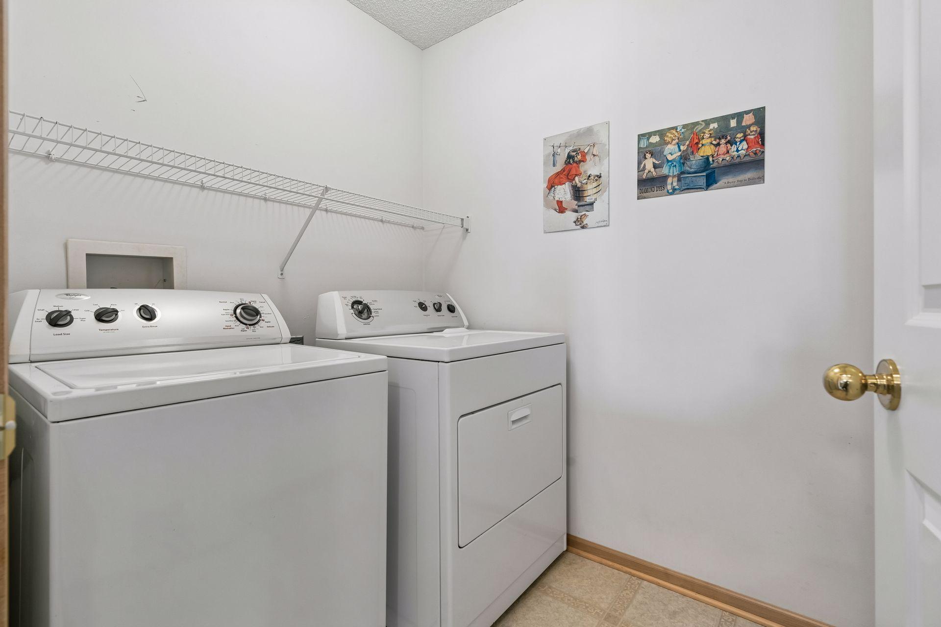 Fabulous laundry room with a white washer/dryer and storage shelving above.