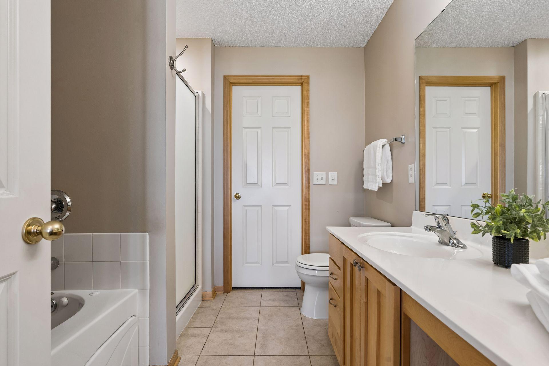 Primary bath with a tile floor, large vanity, soaking tub, separate shower and walk-in closet within.