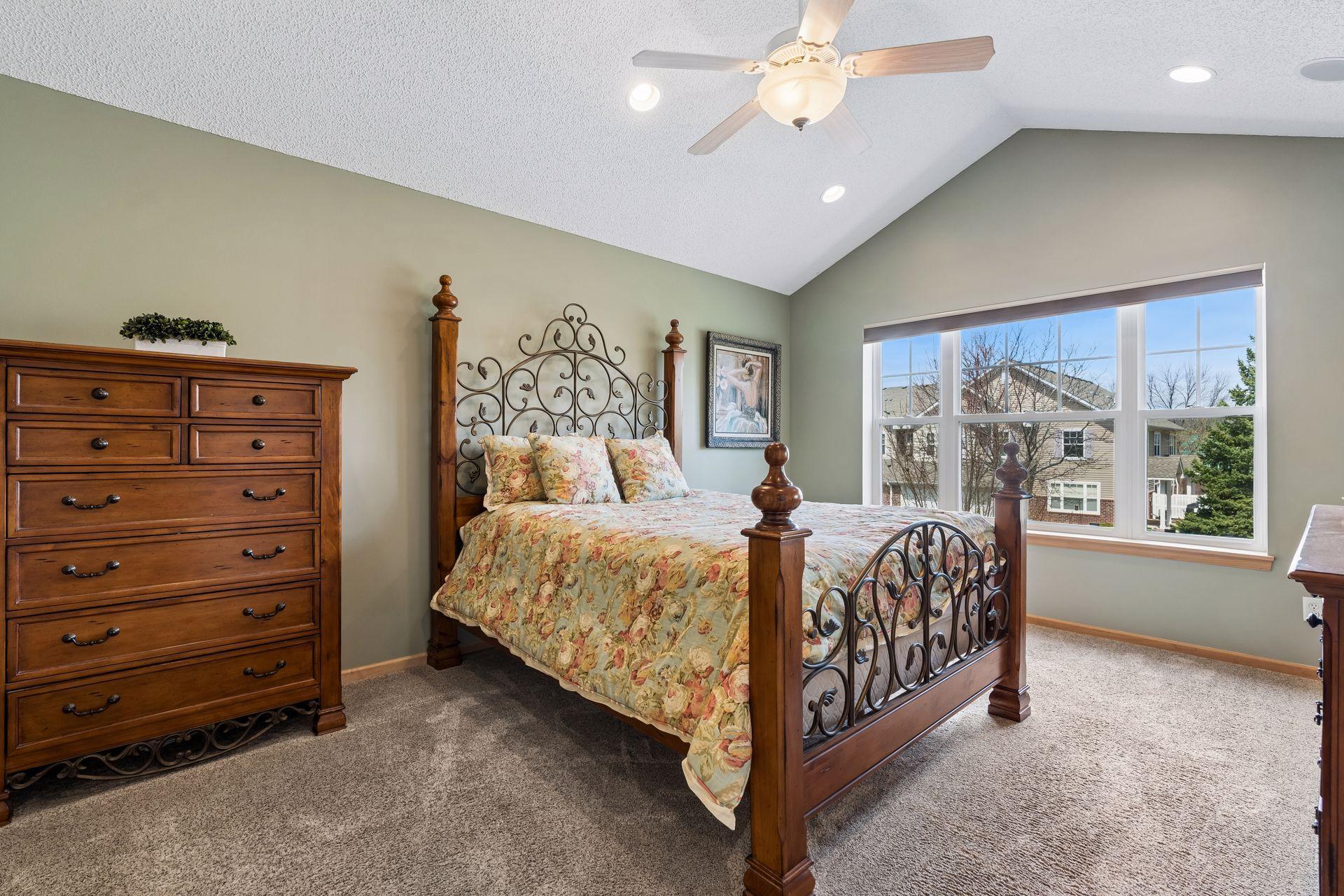 Spacious primary suite with a vaulted ceiling, ceiling fan and large window presentation.
