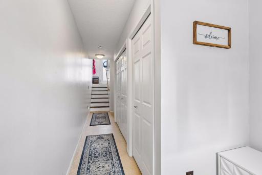 View from back door to stairs leading to the front door. The white closet doors access the furnace, water heater and water softener.