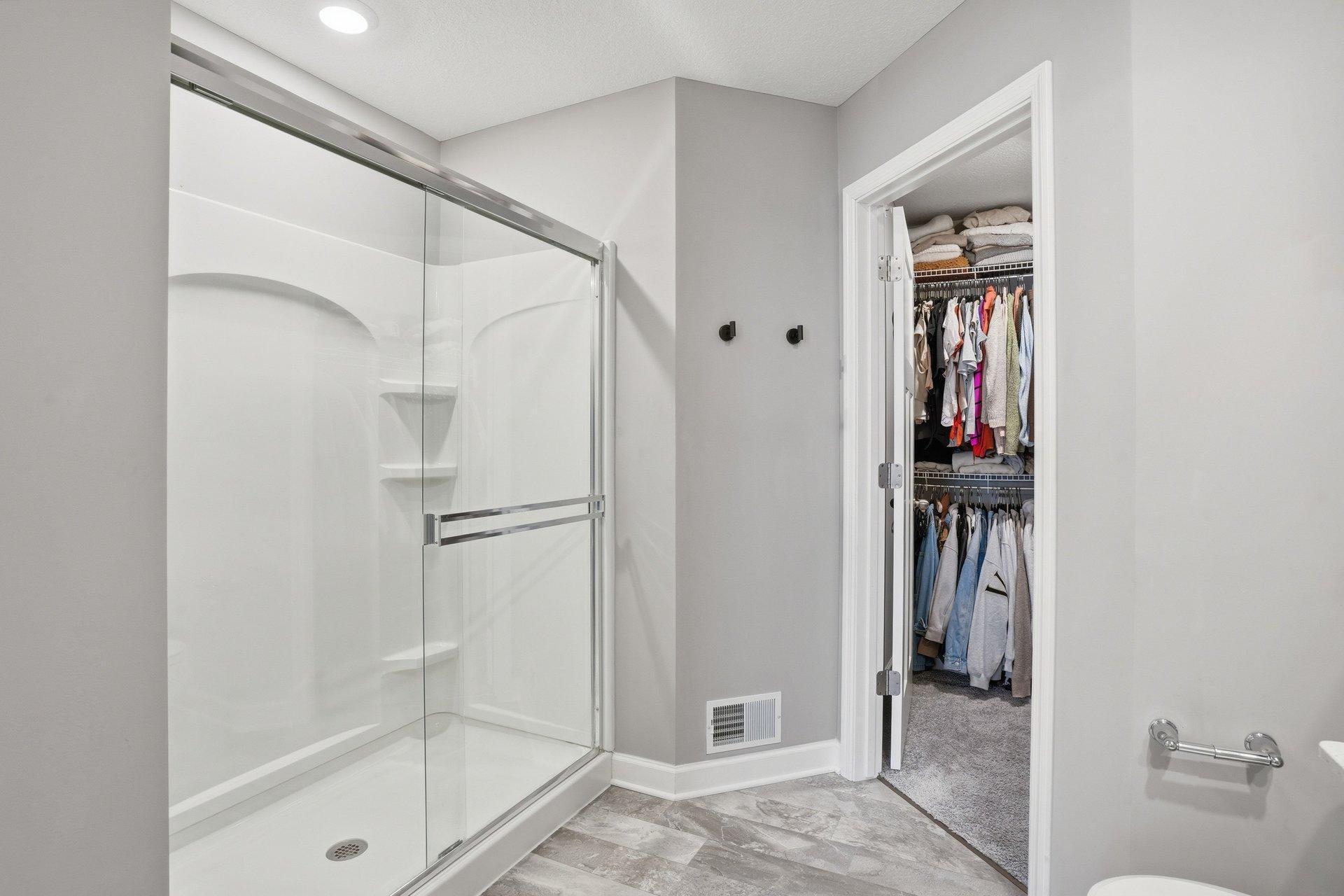 Walk-in shower with glass sliding doors and walk-in closet.