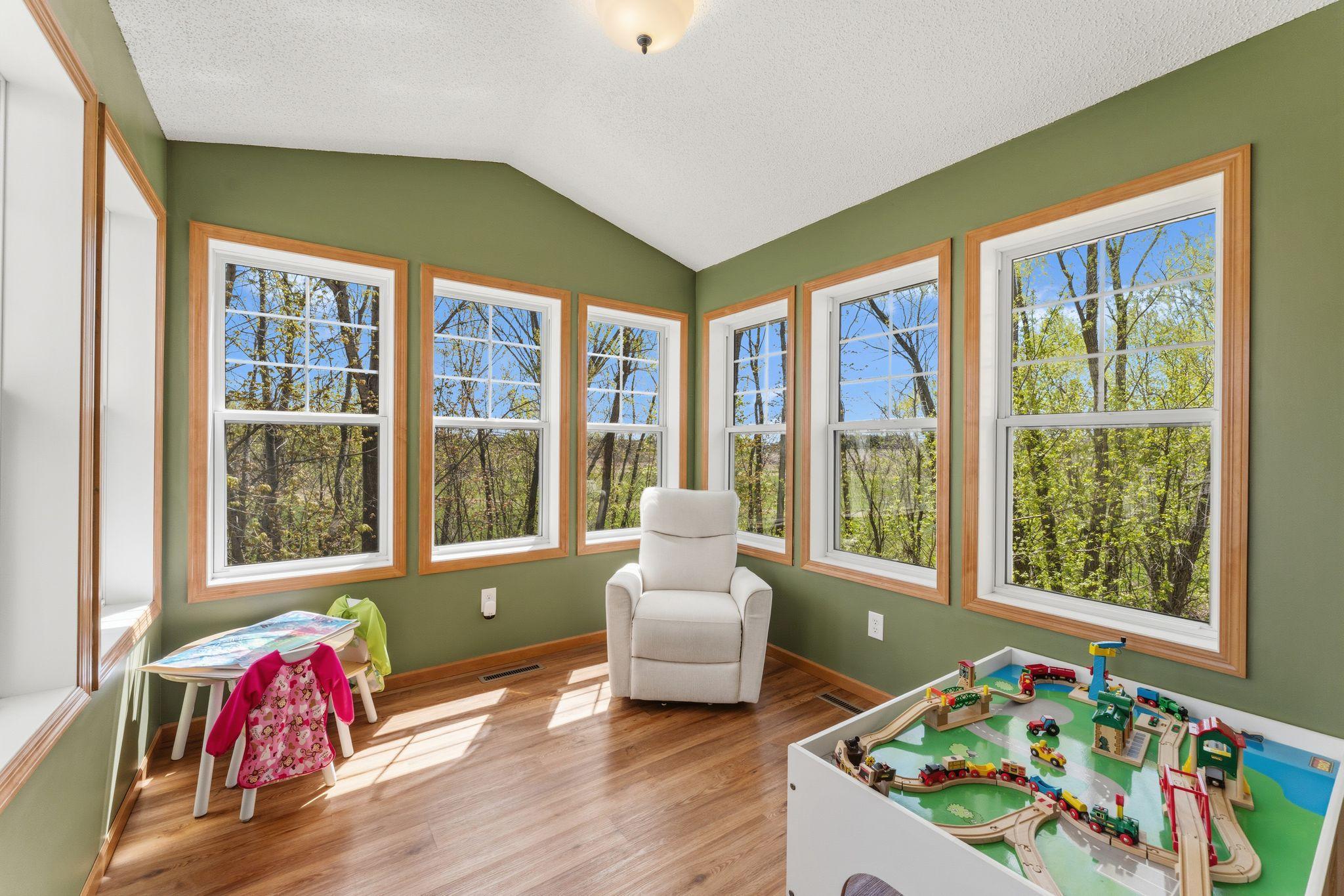 Bright sunroom filled with windows, offering beautiful nature views and lots of natural light