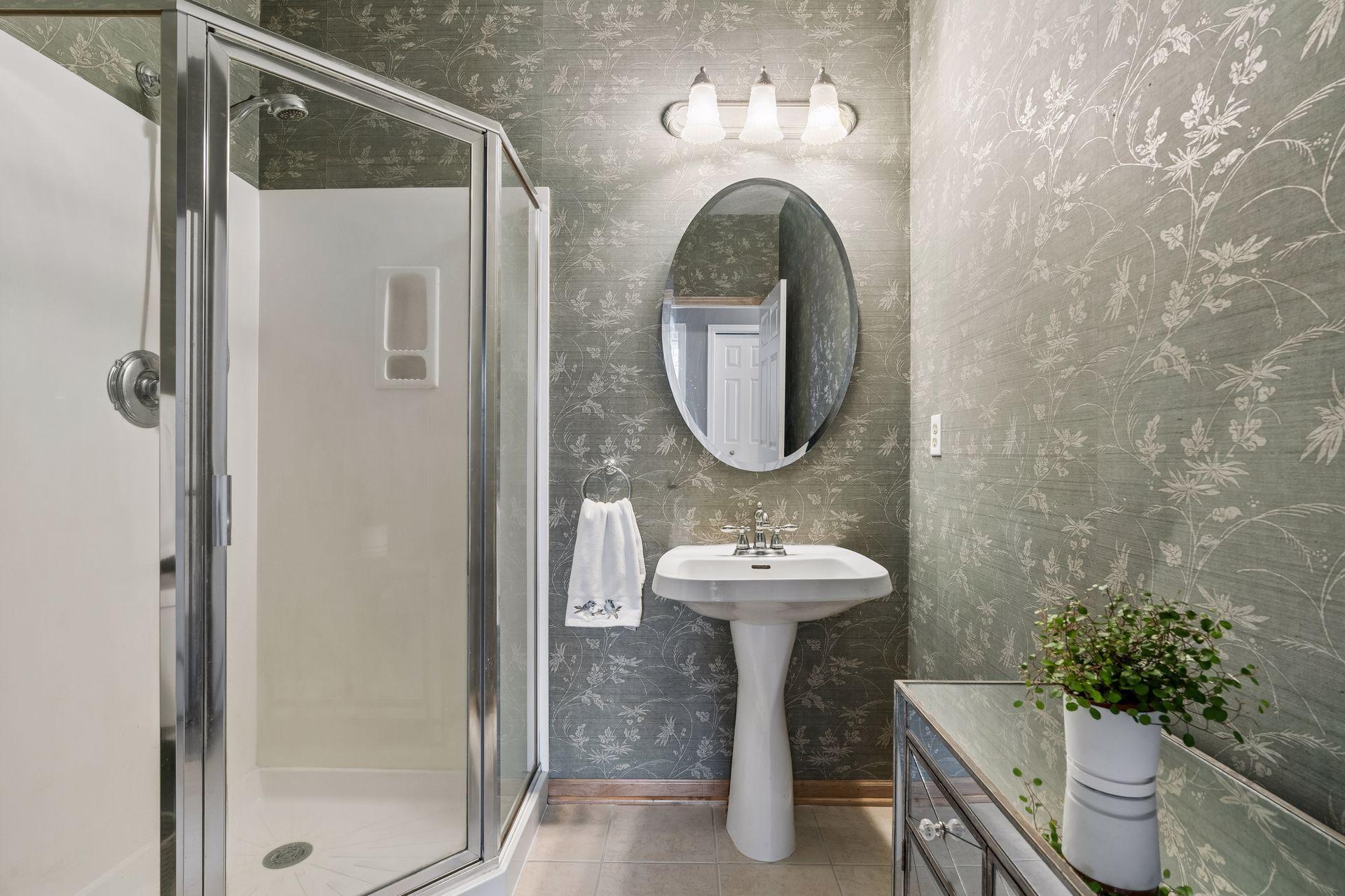 Elevated 3/4 bath with bold wallpaper creating a high-end, custom feel.