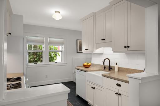 White ceramic farmhouse sink with stone countertops.