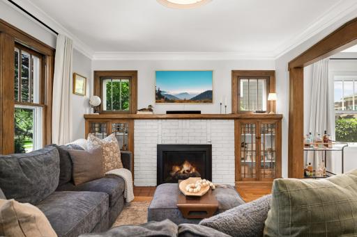 Tons of character in living room with updated gas fireplace that is flanked with built-in cabinets and boxed windows.
