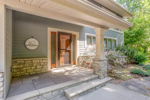 Covered front porch welcomes guests with attractive stone accents and a warm, inviting entrance.