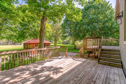 Multiple outdoor living areas include a spacious deck, patio, and beautifully landscaped surroundings.