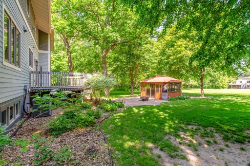 Enjoy a private backyard oasis featuring mature trees, expansive green space, and a charming screened gazebo.