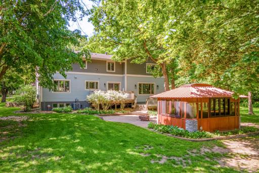 Private 1.28-acre backyard retreat featuring mature trees, a spacious lawn, and a charming gazebo with hot tub for seasonal enjoyment.