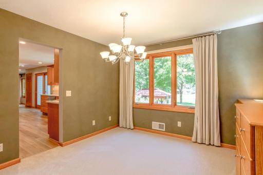 Formal dining room featuring built-in cabinetry, elegant lighting, and large windows overlooking the beautifully landscaped yard.