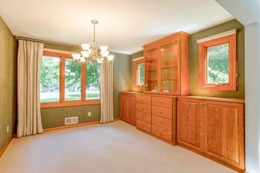 Elegant dining room with custom built-in cabinetry, display shelving, and large windows that bring in an abundance of natural light.