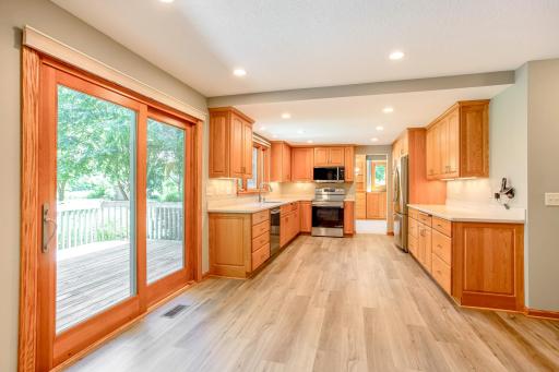 Bright and spacious kitchen featuring abundant cabinetry, expansive counter space, recessed lighting, and sliding glass doors leading to the backyard deck.